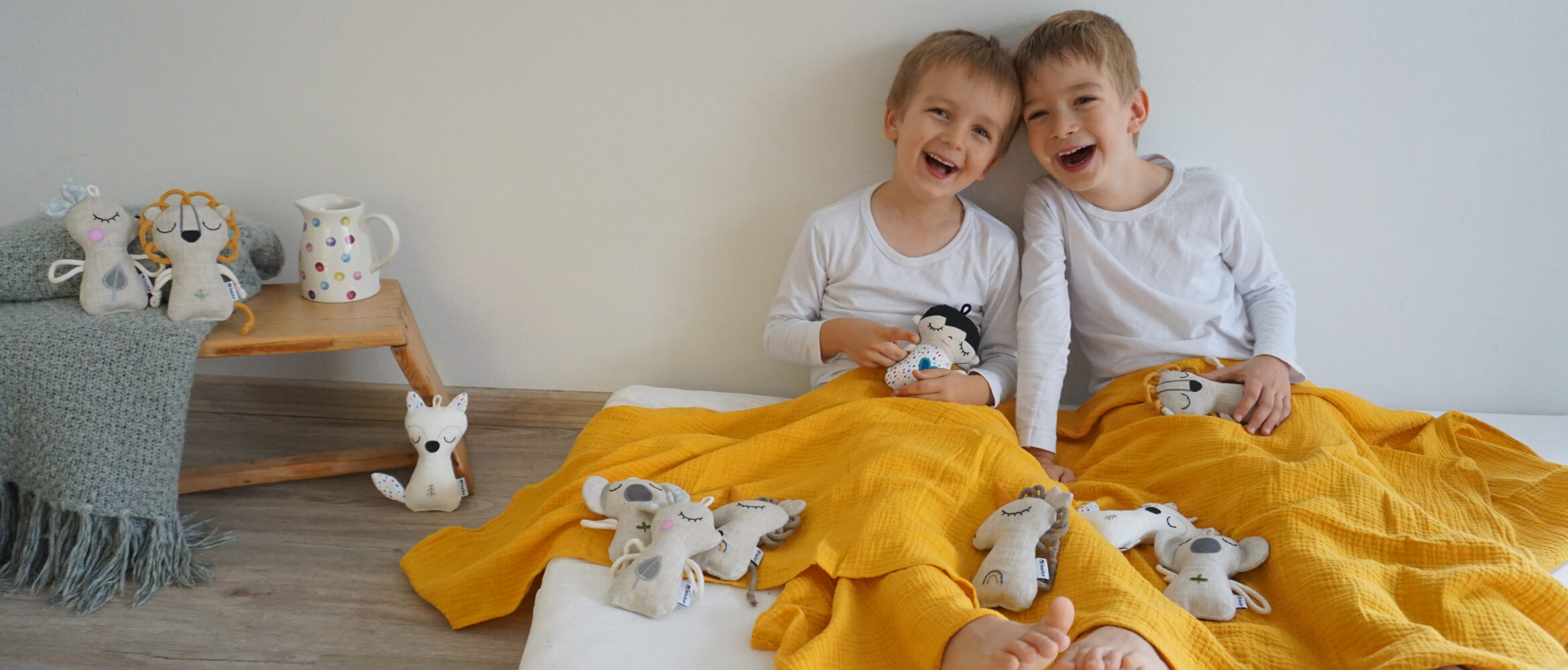 dva chlapci sedí mezi šitými hračkami a smějí se